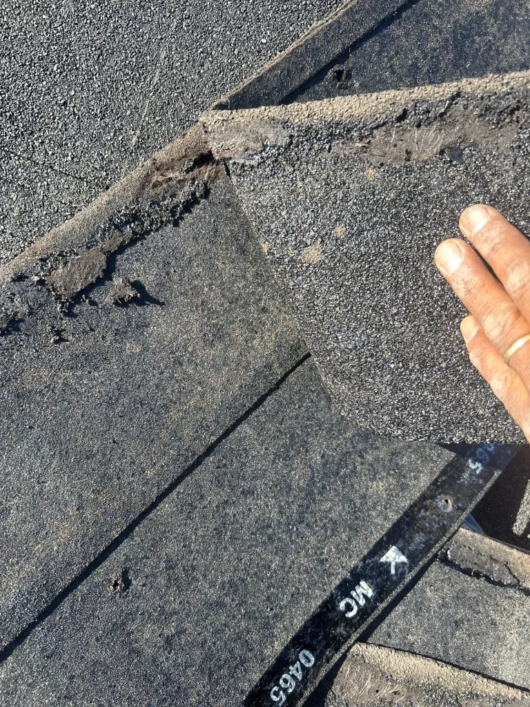 Close-up of damaged shingles exposing underlayment on a Louisville, KY roof.