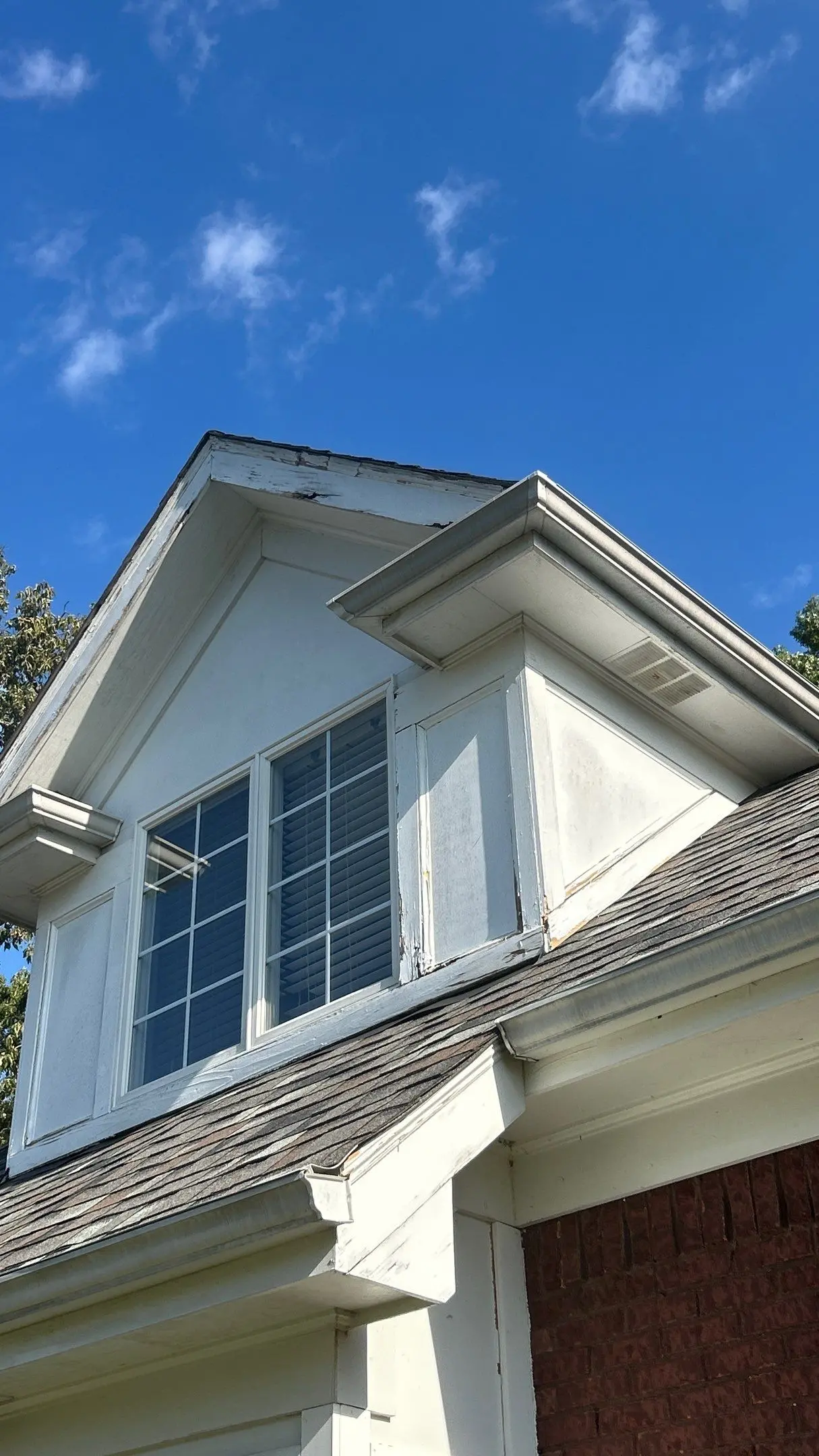 Dormer with wood rot, peeling paint, and damaged trim on a Louisville, KY home needing repair.