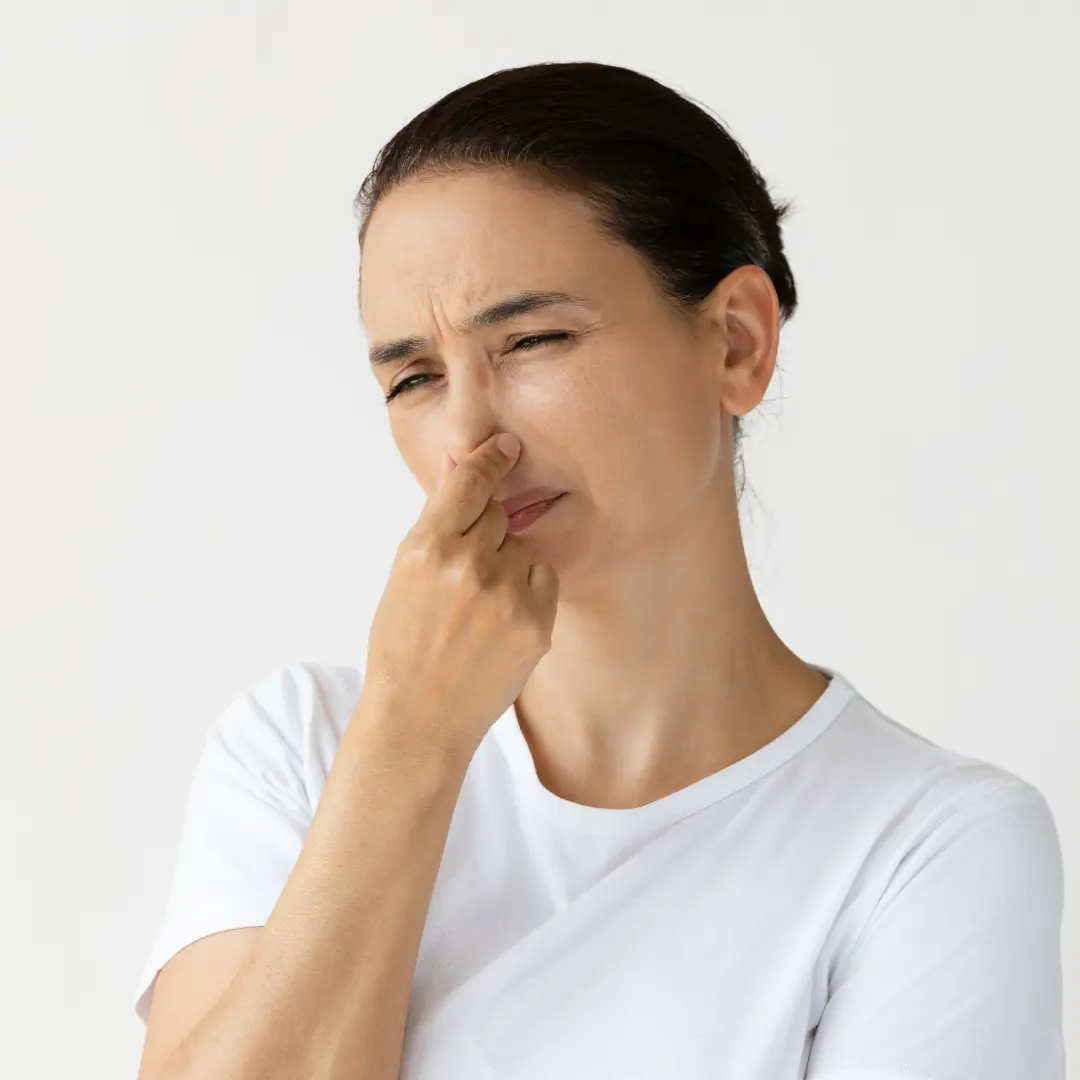 Woman holding her nose due to a strong musty smell inside her La Grange KY home caused by moisture from a roof leak
