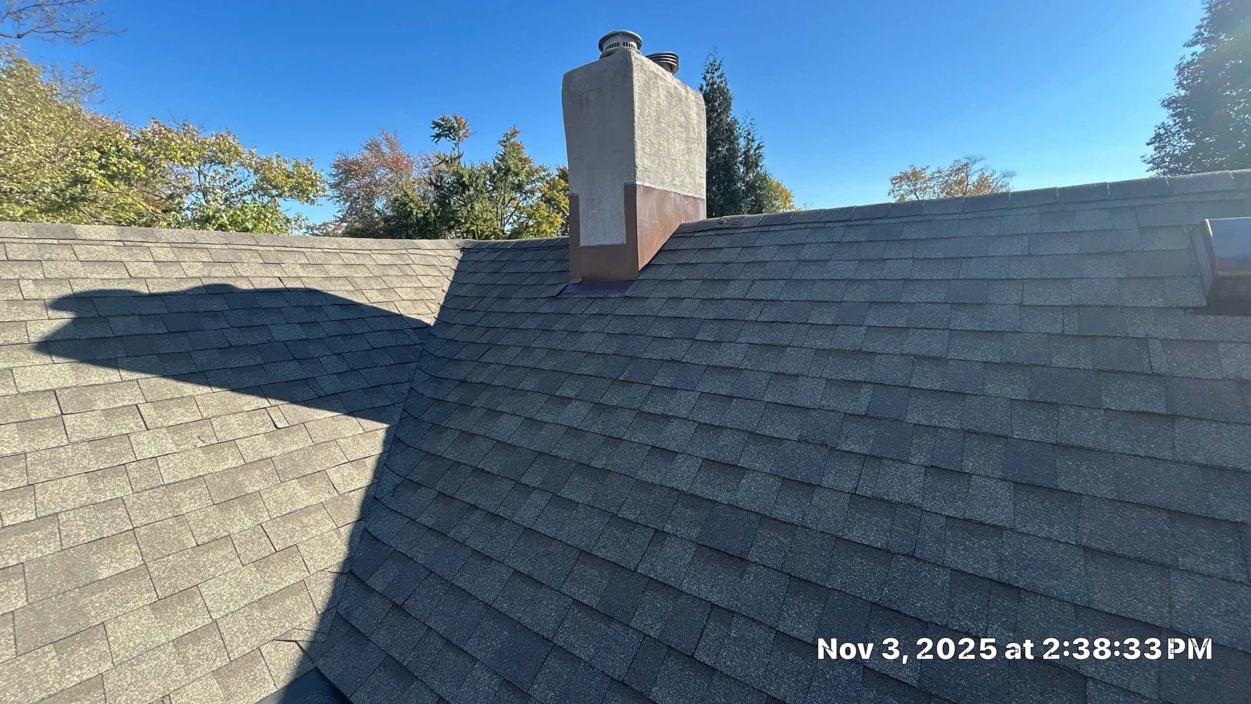 Repaired shingle roof with chimney and strong roofline shadowing on a Louisville, KY home.