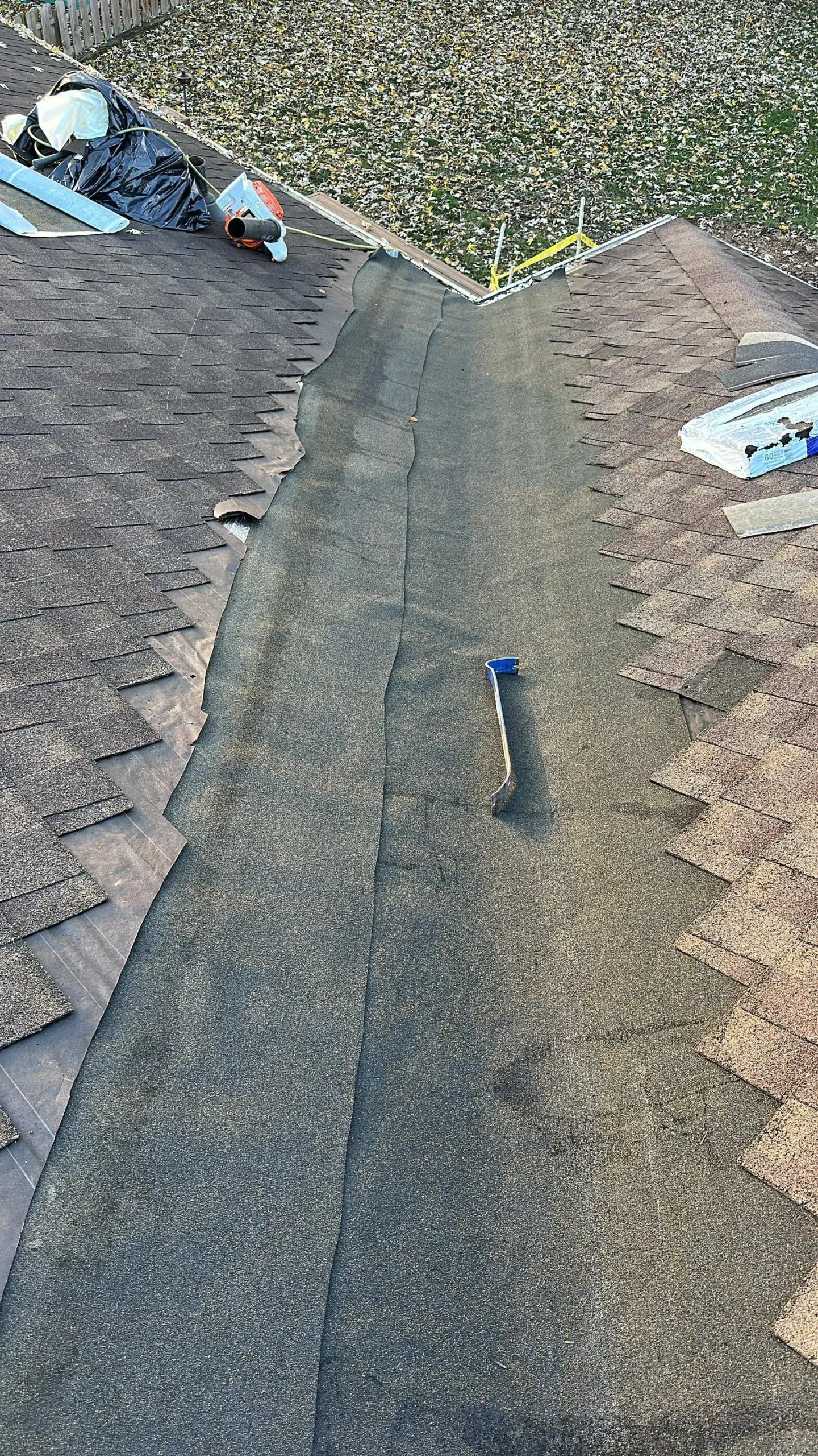 Exposed roof valley underlayment with lifted shingles and tools visible during a roof repair on a Louisville KY home