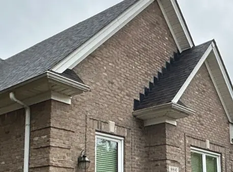 Front view of a brick Louisville KY home with white gutters, downspouts, and clean architectural rooflines.