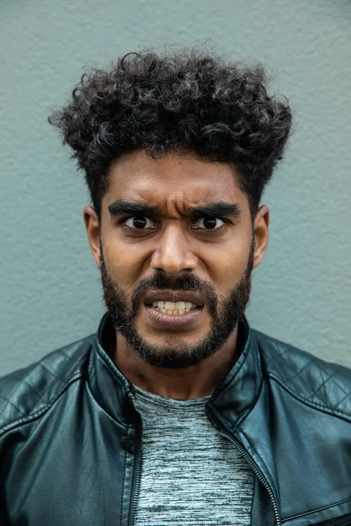 Portrait of a man with curly hair and intense facial expression wearing a leather jacket
