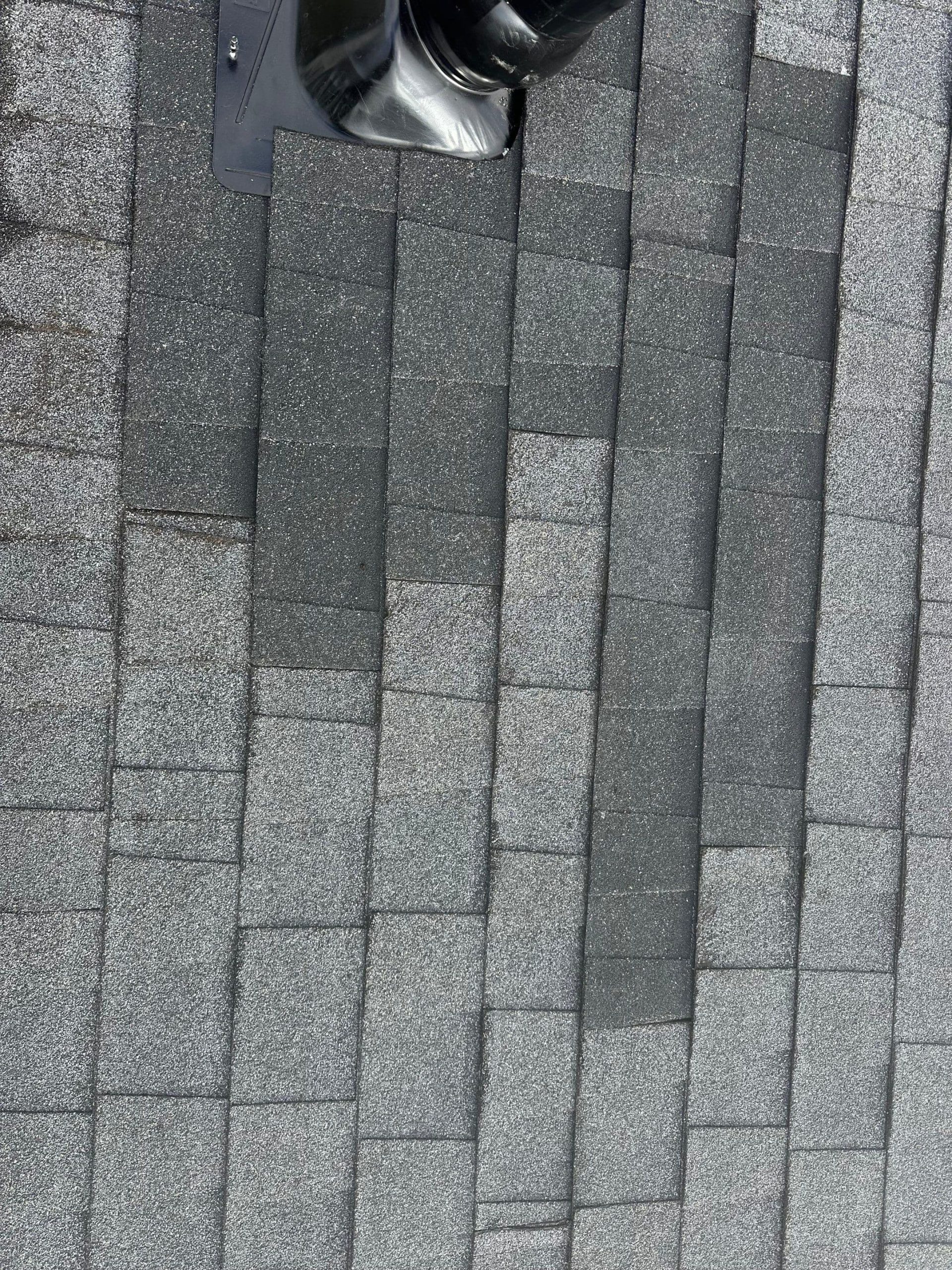 Asphalt roof shingles showing color variation and discoloration after repair