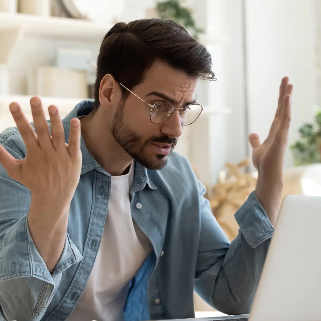 Frustrated homeowner reacting to a home repair issue while looking at a laptop.