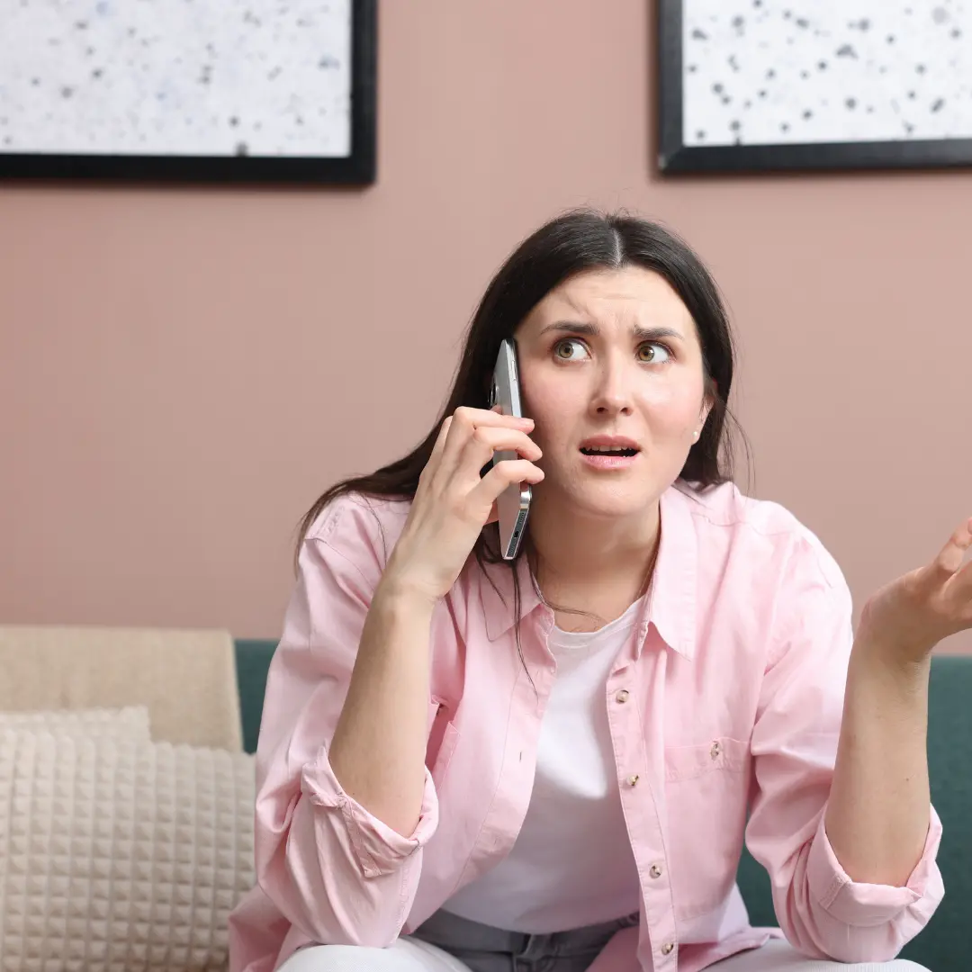 Concerned homeowner on the phone discussing a home repair issue caused by a potential roof leak.
