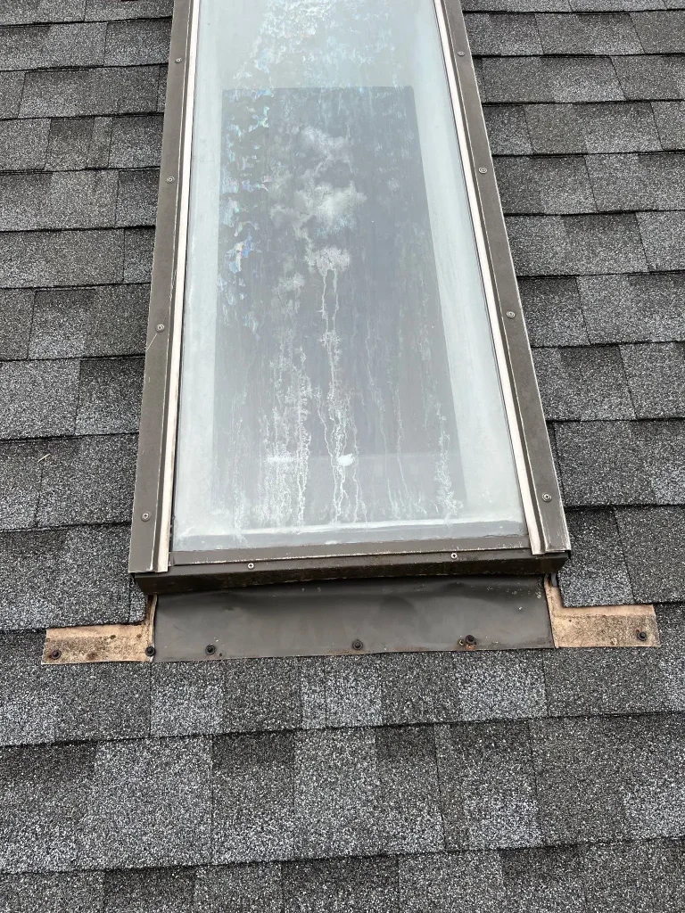 Worn skylight flashing and exposed roof decking around skylight on asphalt shingle roof in Lexington KY