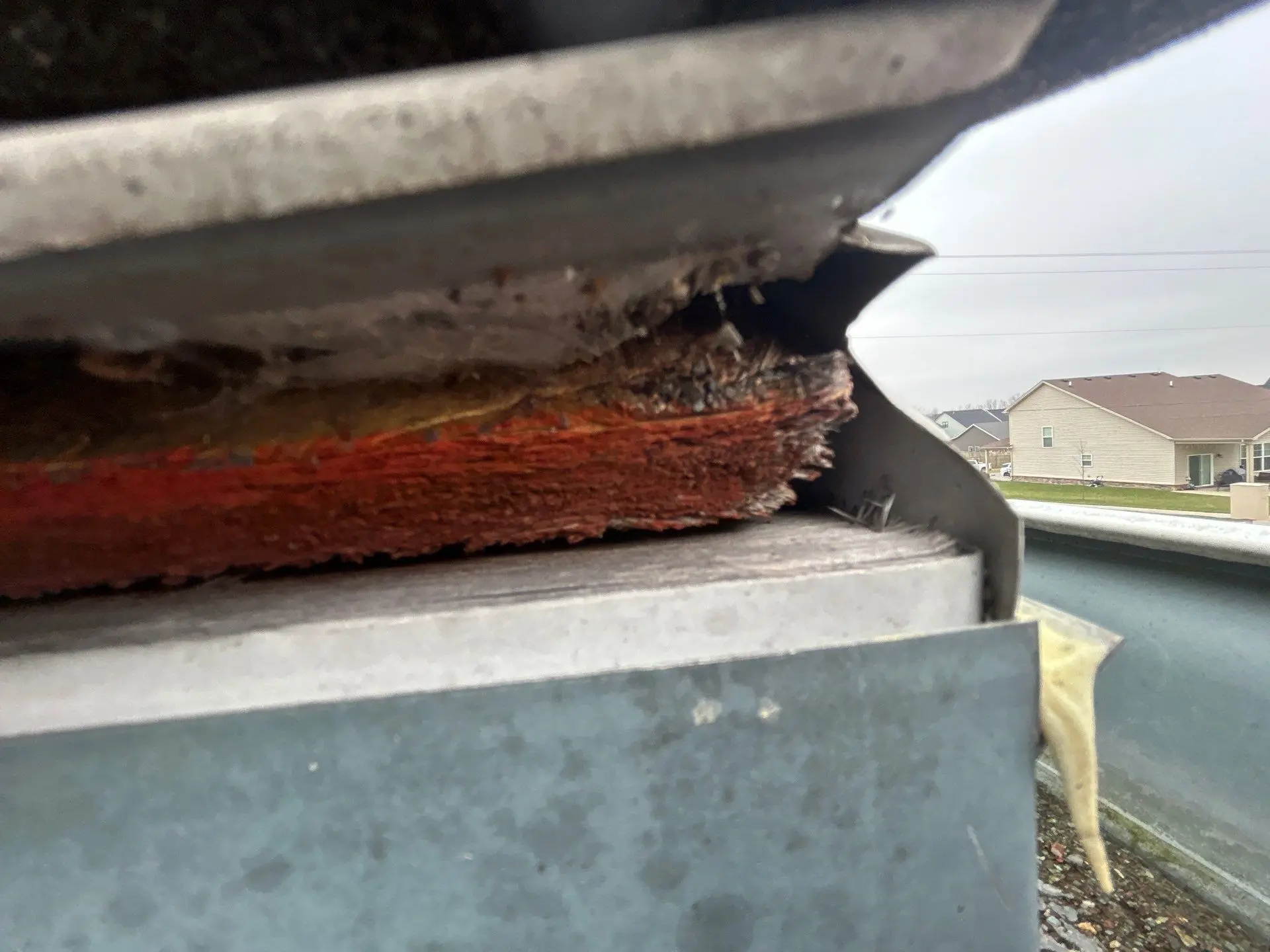 Rotted wooden fascia board behind damaged gutter system caused by prolonged water exposure.