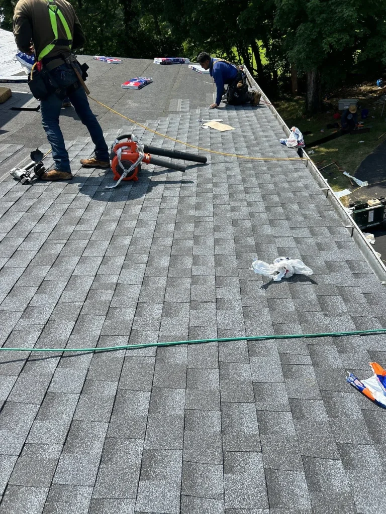 Roofers repairing asphalt shingles and blending new shingles into existing roof in Lexington KY
