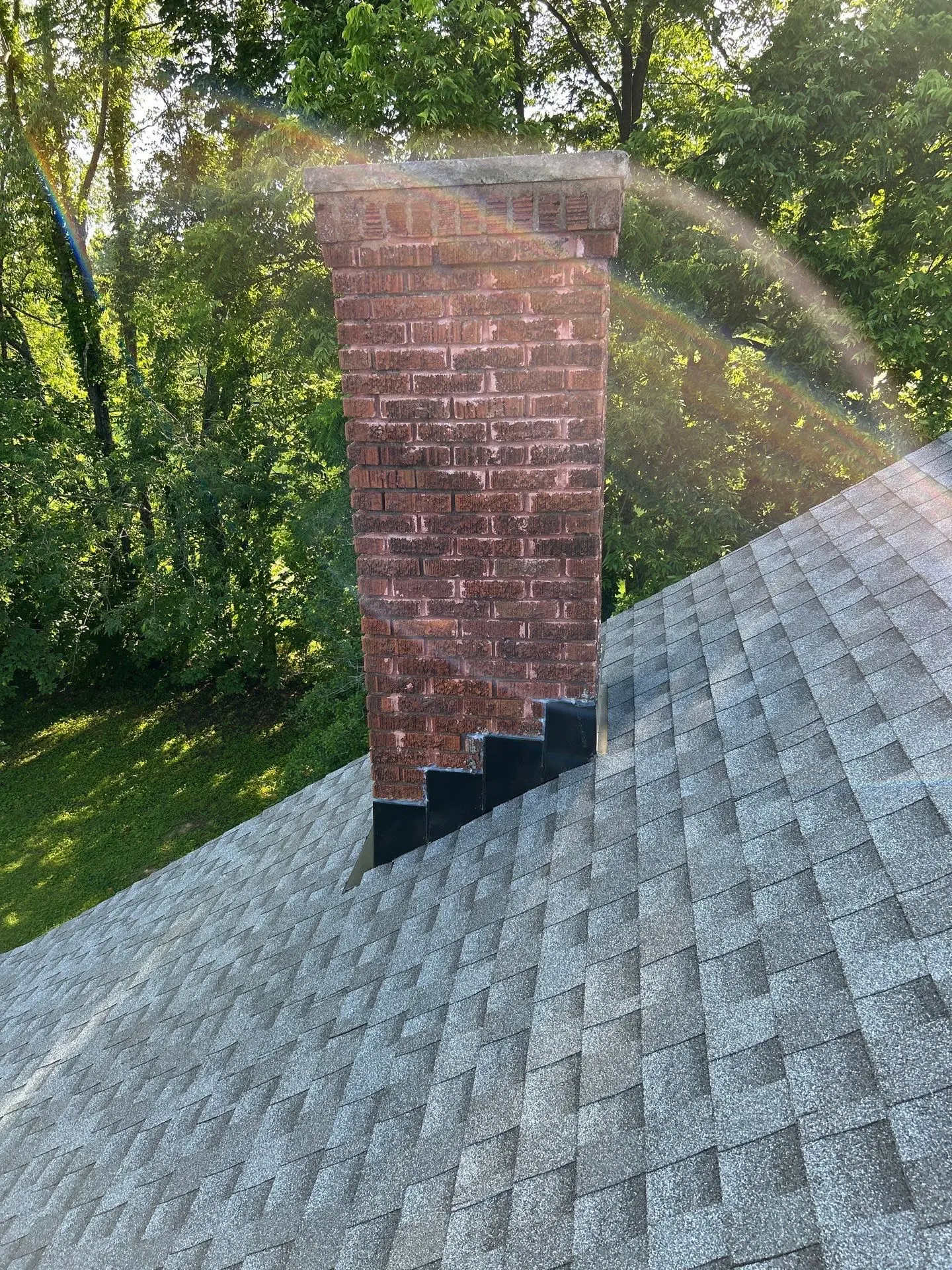 Chimney flashing installation on asphalt shingle roof in Lexington KY with step flashing