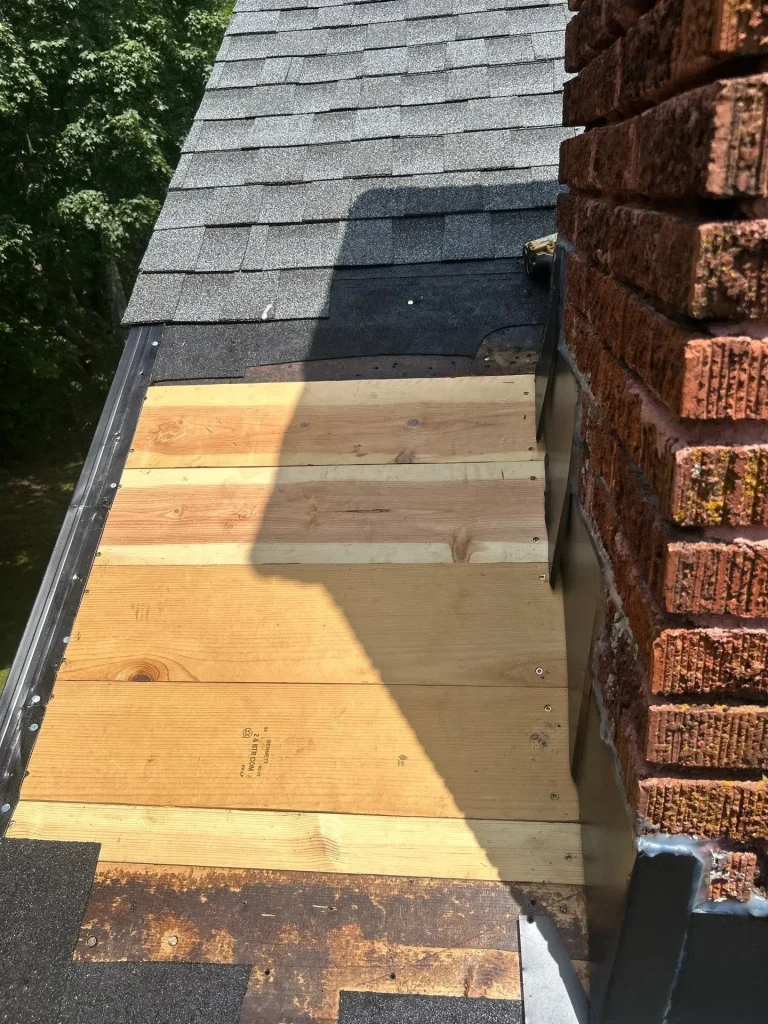 Missing shingles exposing roof decking near chimney on asphalt roof in Lexington KY