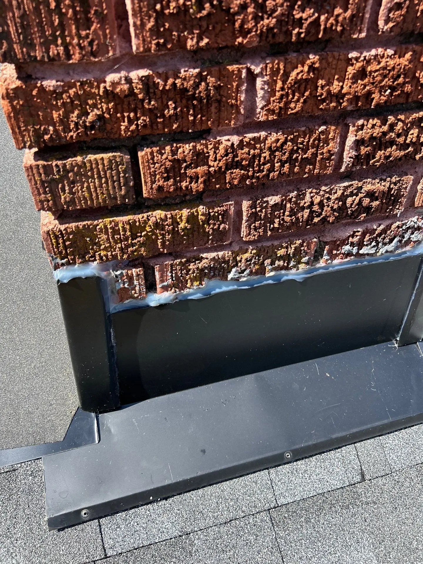 Roof flashing installation along brick wall in Lexington KY with step flashing and sealant