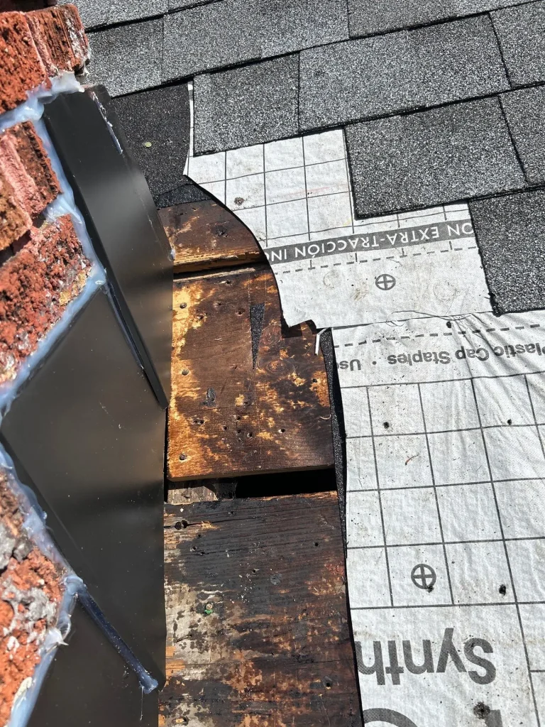 Damaged roof shingles and exposed decking near wall flashing in Lexington KY