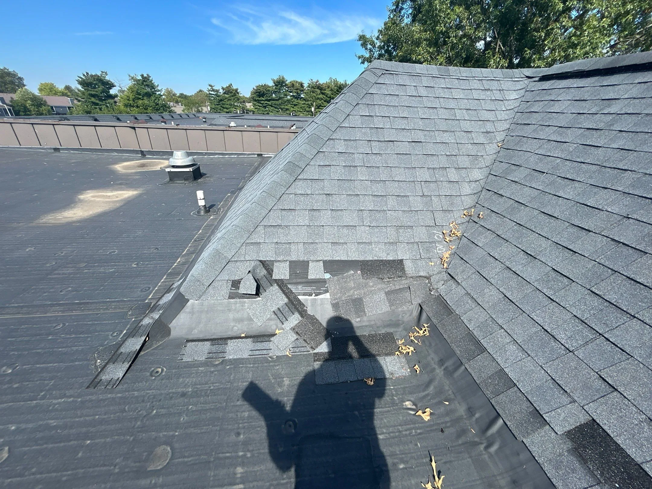 Damaged shingles on a mansard roof meeting a flat membrane roof on a commercial building in Irvine, KY