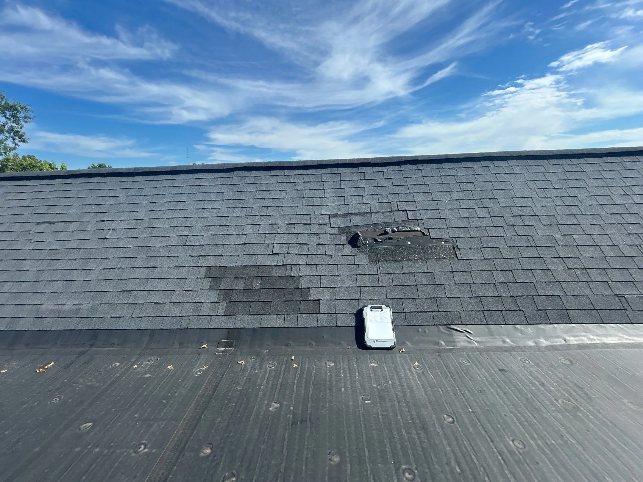 Missing shingles and exposed flashing on a commercial shingle roof in Irvine, KY