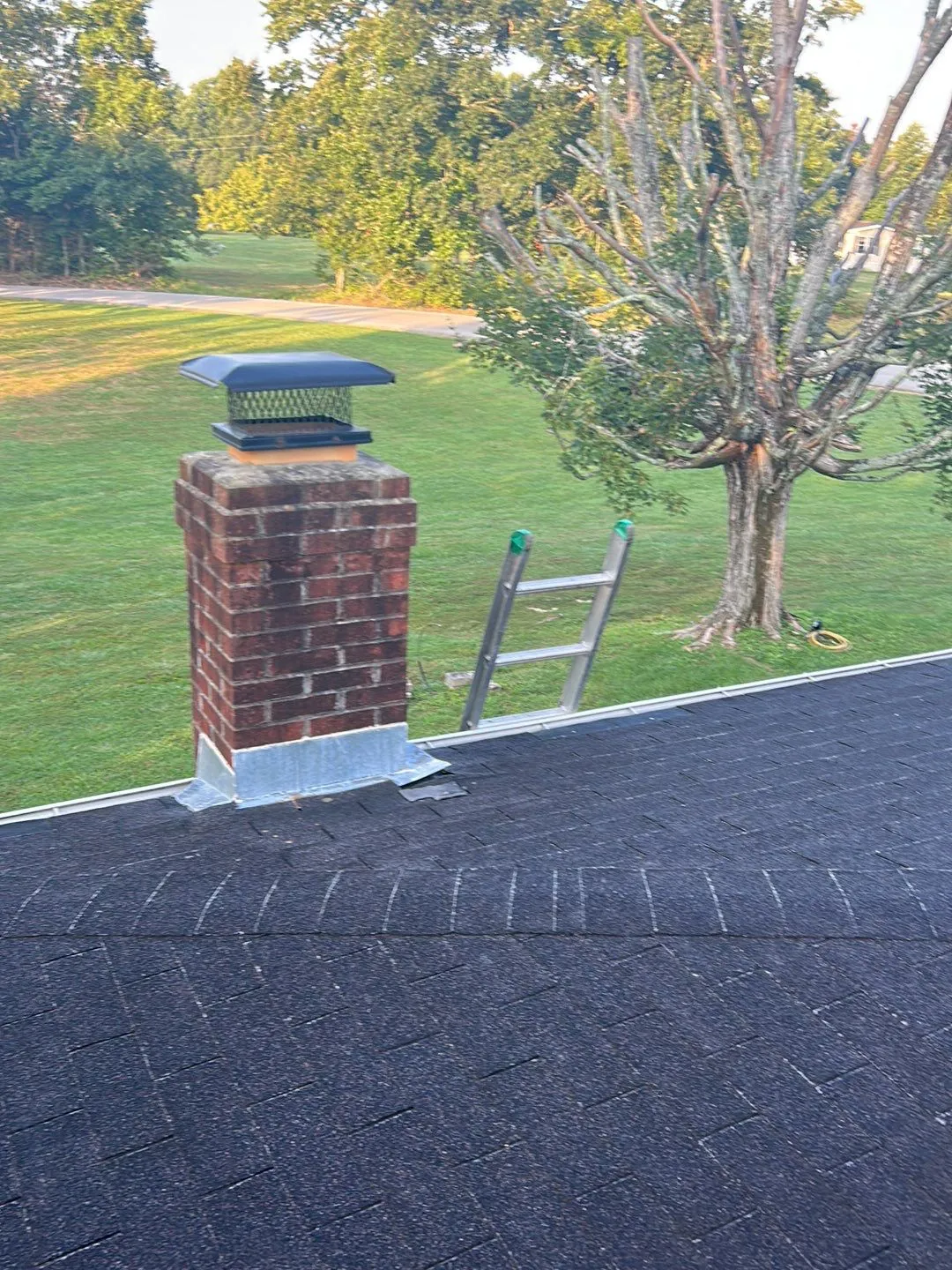 Brick chimney with a black chimney cap and base flashing in Irvine, KY