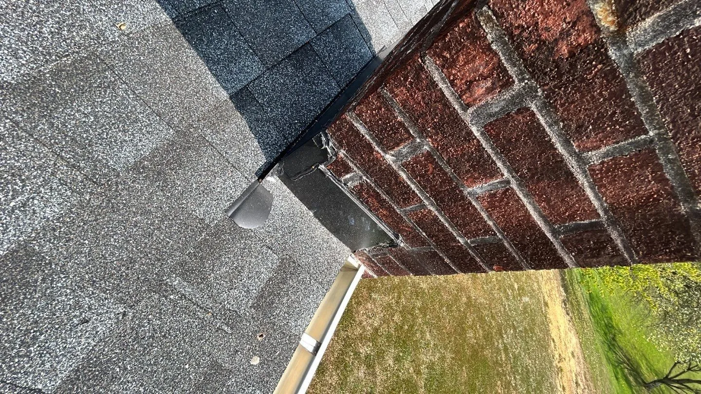 Gray shingle roof meeting a red brick wall with flashing and gutter in Irvine, KY