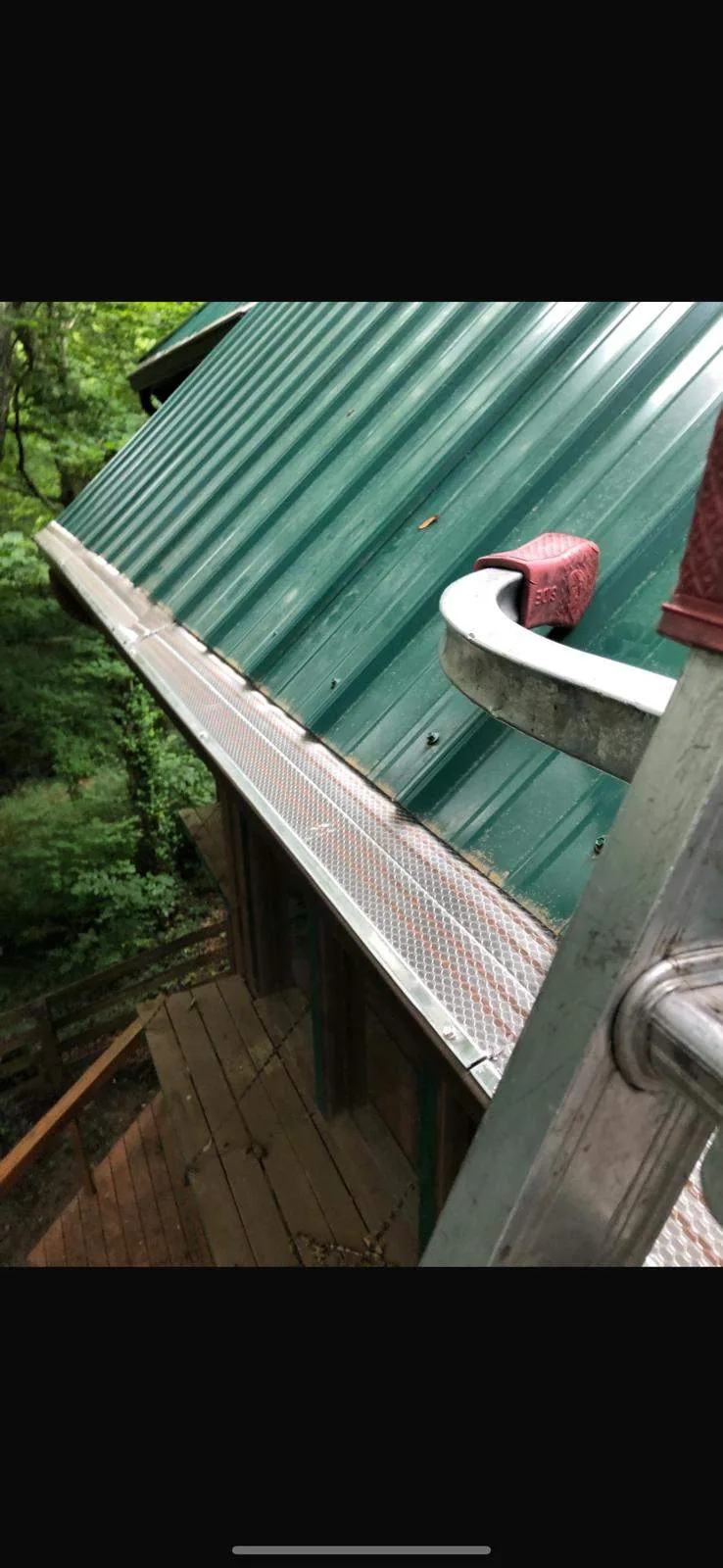 Mesh gutter guard installed along a green metal roof, surrounded by trees, on a Mt. Sterling, KY home.