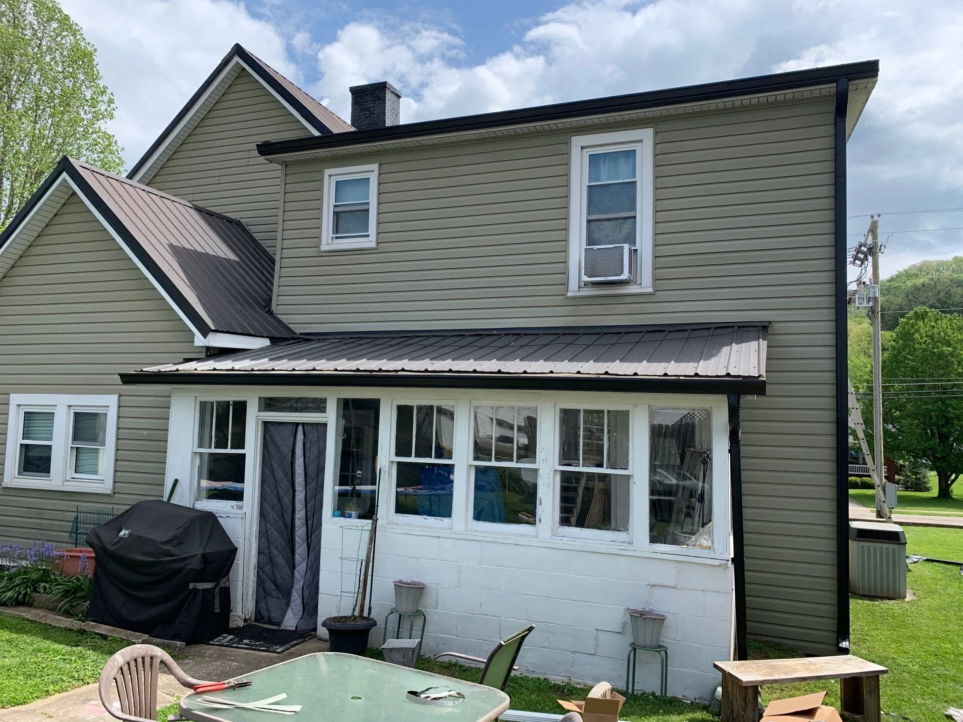 Newly installed black seamless gutters on a green-sided home in Irvine, KY.