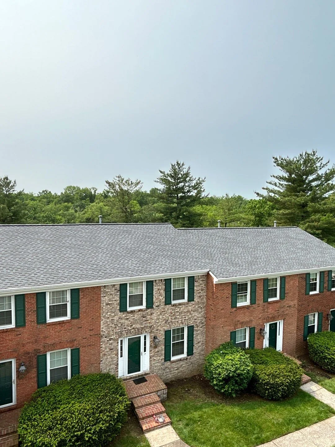 Brick multi-family building in Richmond, KY with a new shingle roof and protected landscaping