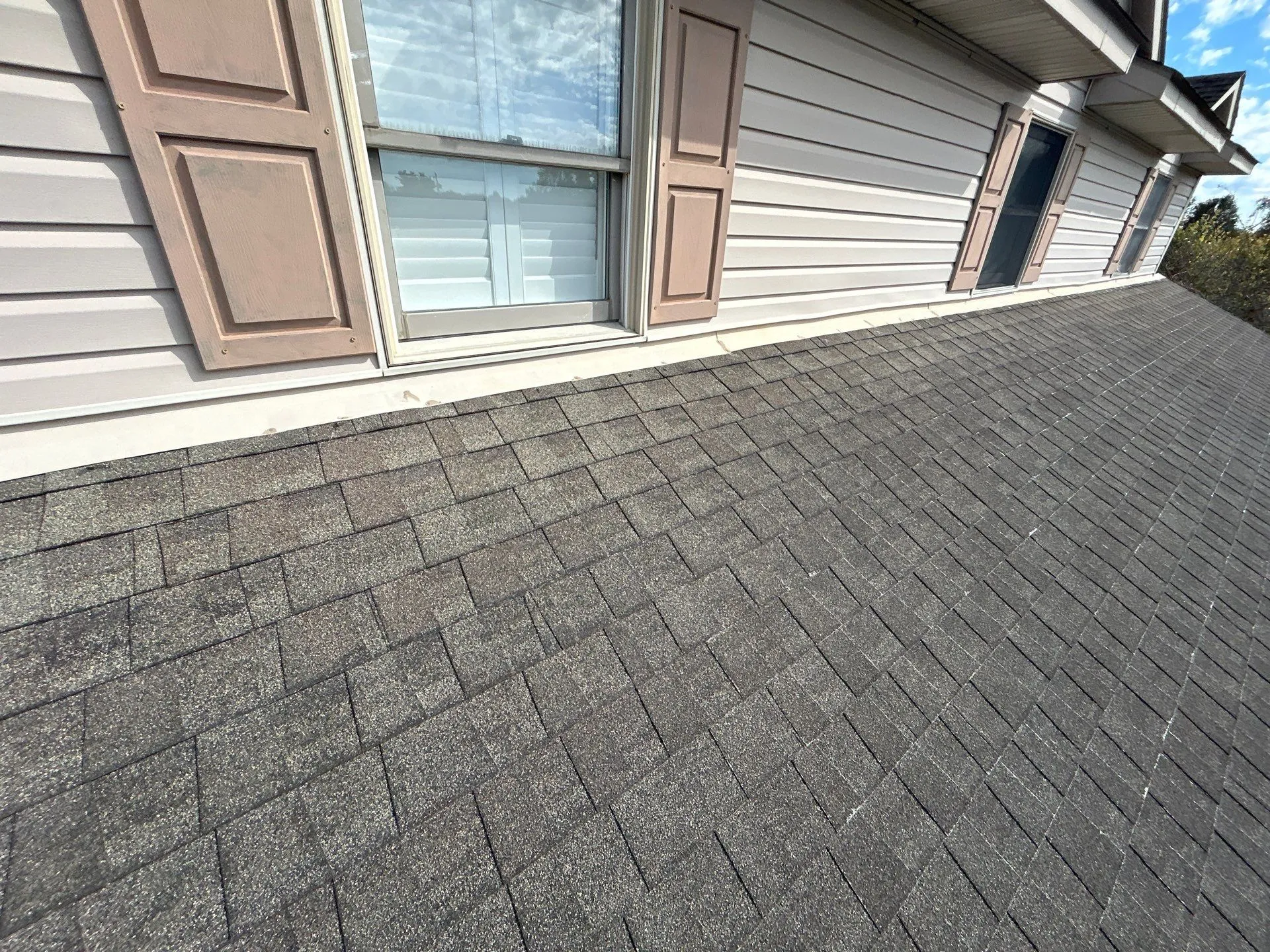 Weathered low-slope shingle roof meeting tan siding with shuttered windows in Mt. Sterling, KY