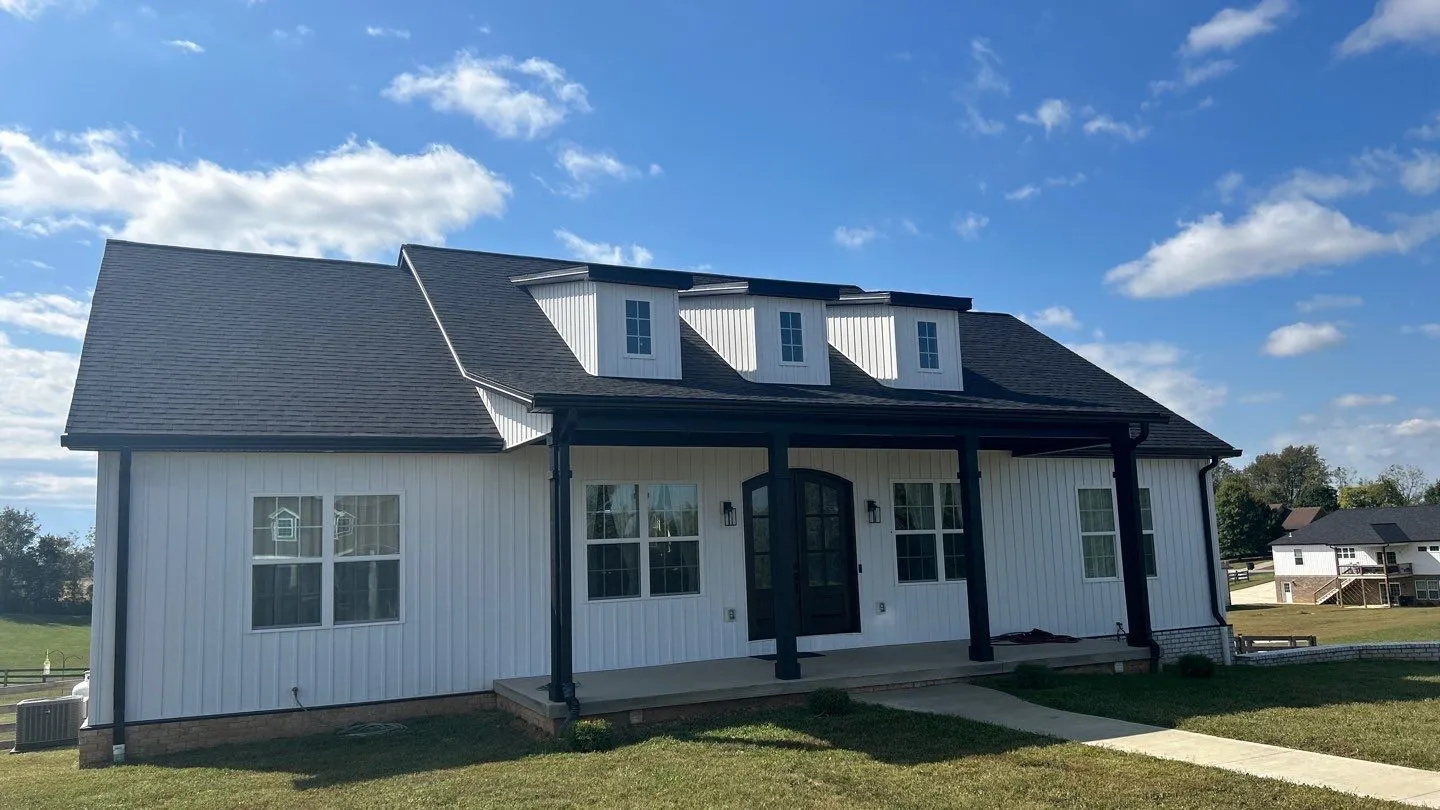 White modern farmhouse with a dark shingle roof and dormers in Lancaster, KY