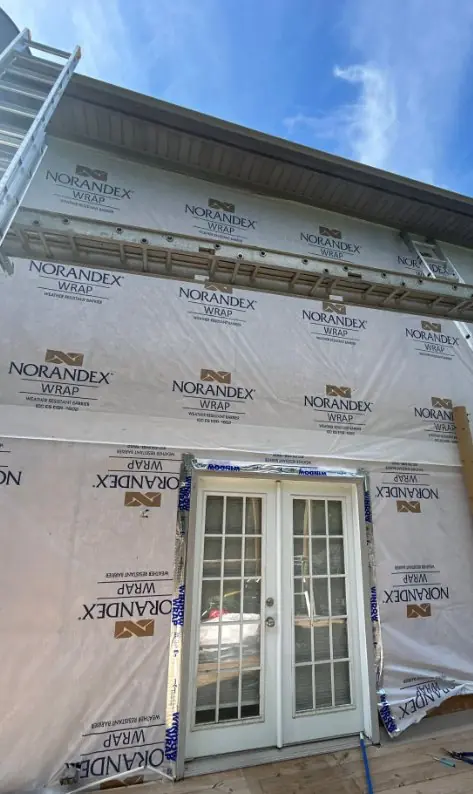 Home wrapped in a weather-resistant barrier during a siding installation before panels go on