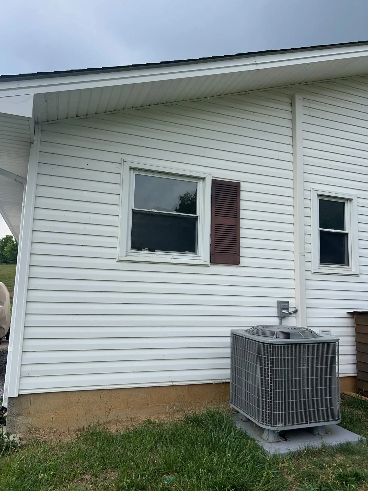 White vinyl siding with windows and a shutter beside an AC unit in Irvine, KY