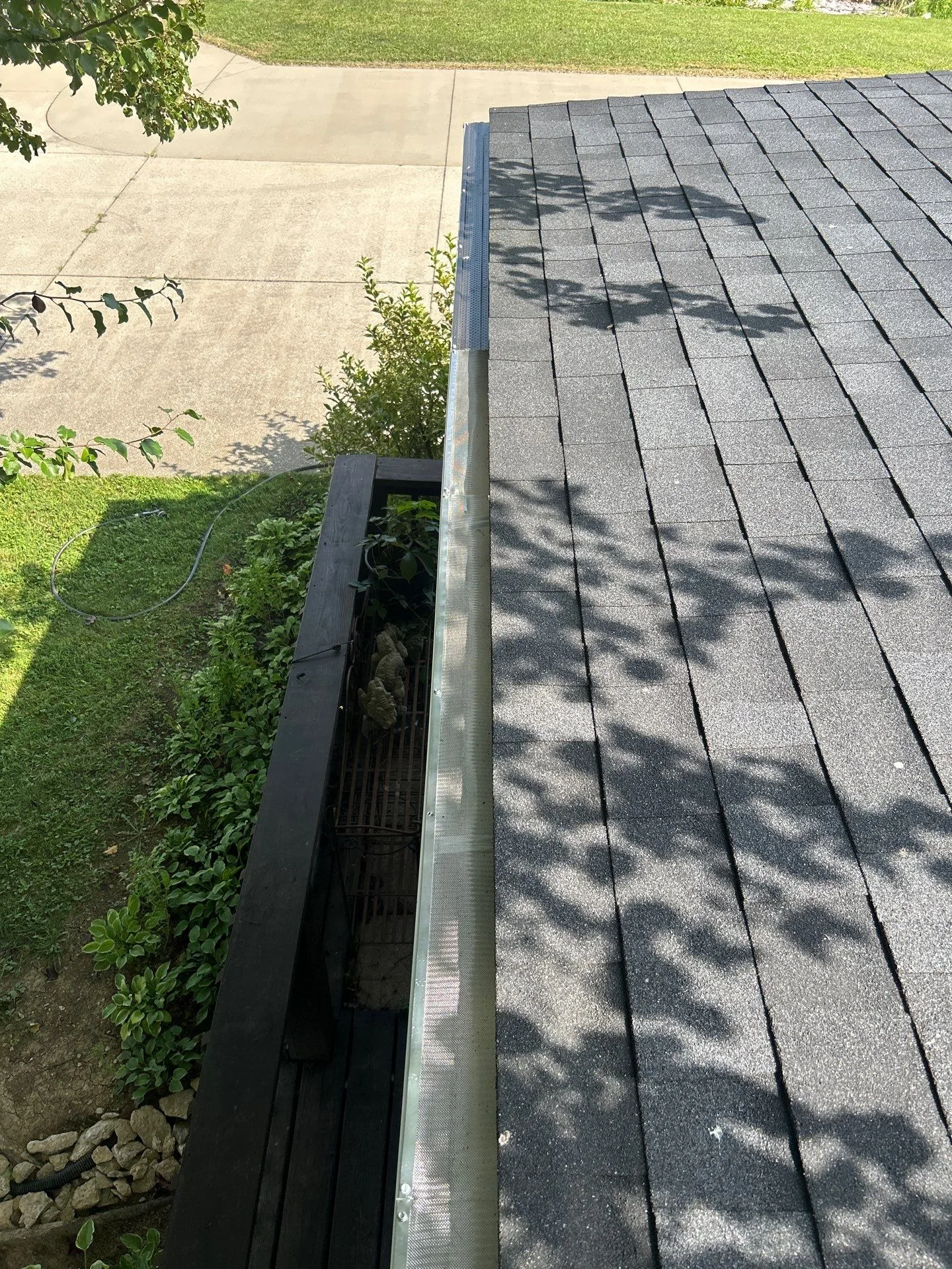 Mesh gutter guard on a shingle roof beside a driveway on a Waco, KY home.