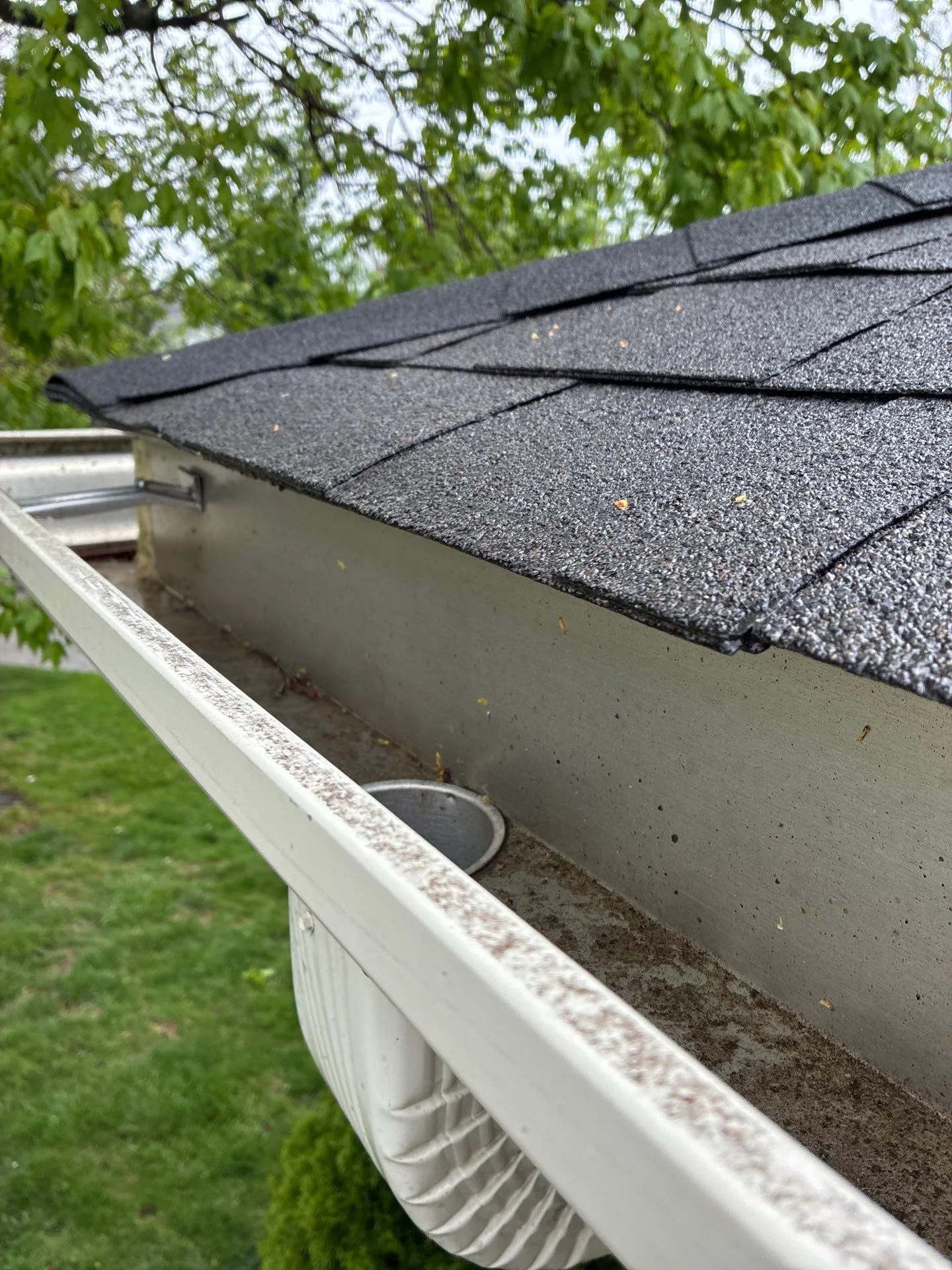 Weathered, stained gutter with a downspout outlet on a Lancaster, KY home.