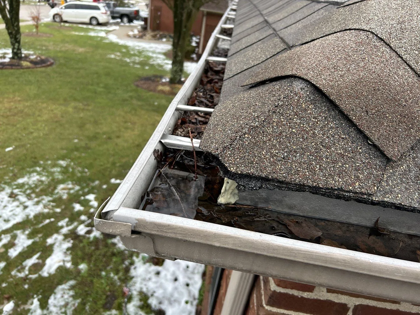 Standing water and leaves pooling in a clogged gutter on a Lancaster, KY home.