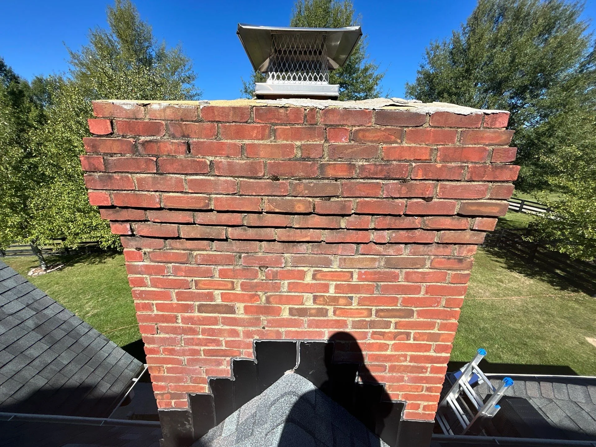 Brick chimney with a deteriorating crown needing repair on a Waco, KY roof.